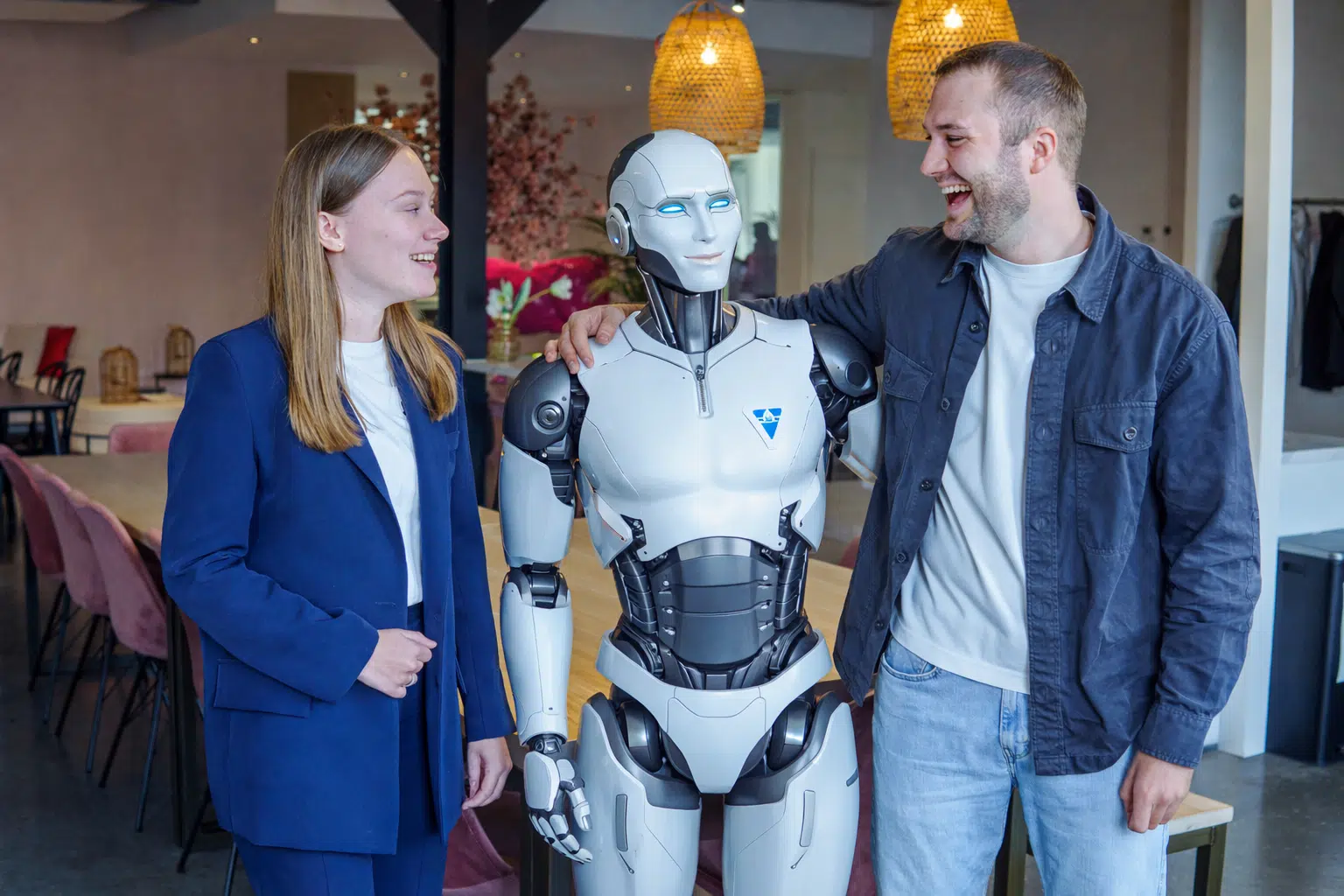 BURO210 Fullservice Marketingbureau Twee mensen met een humanoïde robot in een moderne kantooromgeving, samenwerken bij buro210 en lachen samen.
